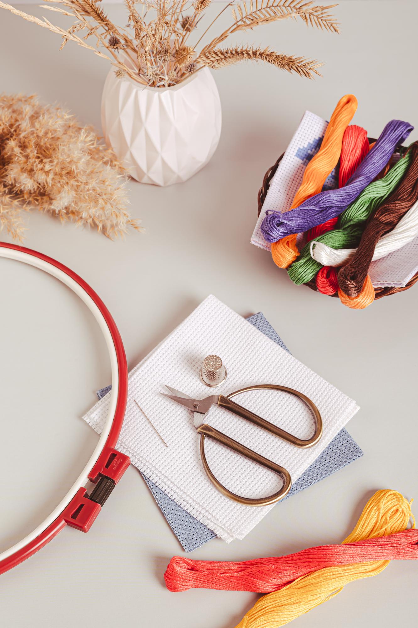 Studio workspace with embroidery hoops and colorful threads on table