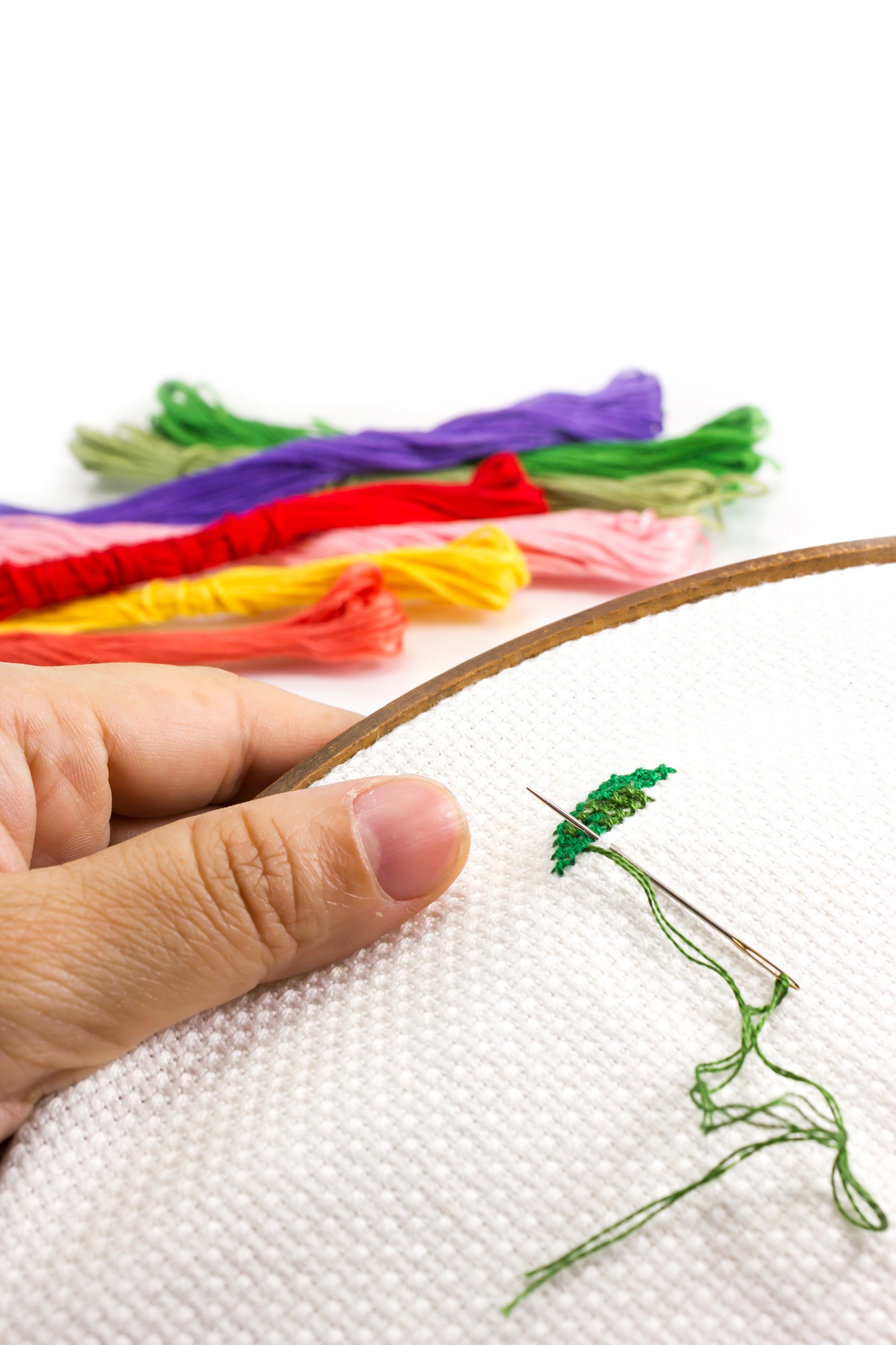Close-up of hands embroidering colorful pattern on fabric