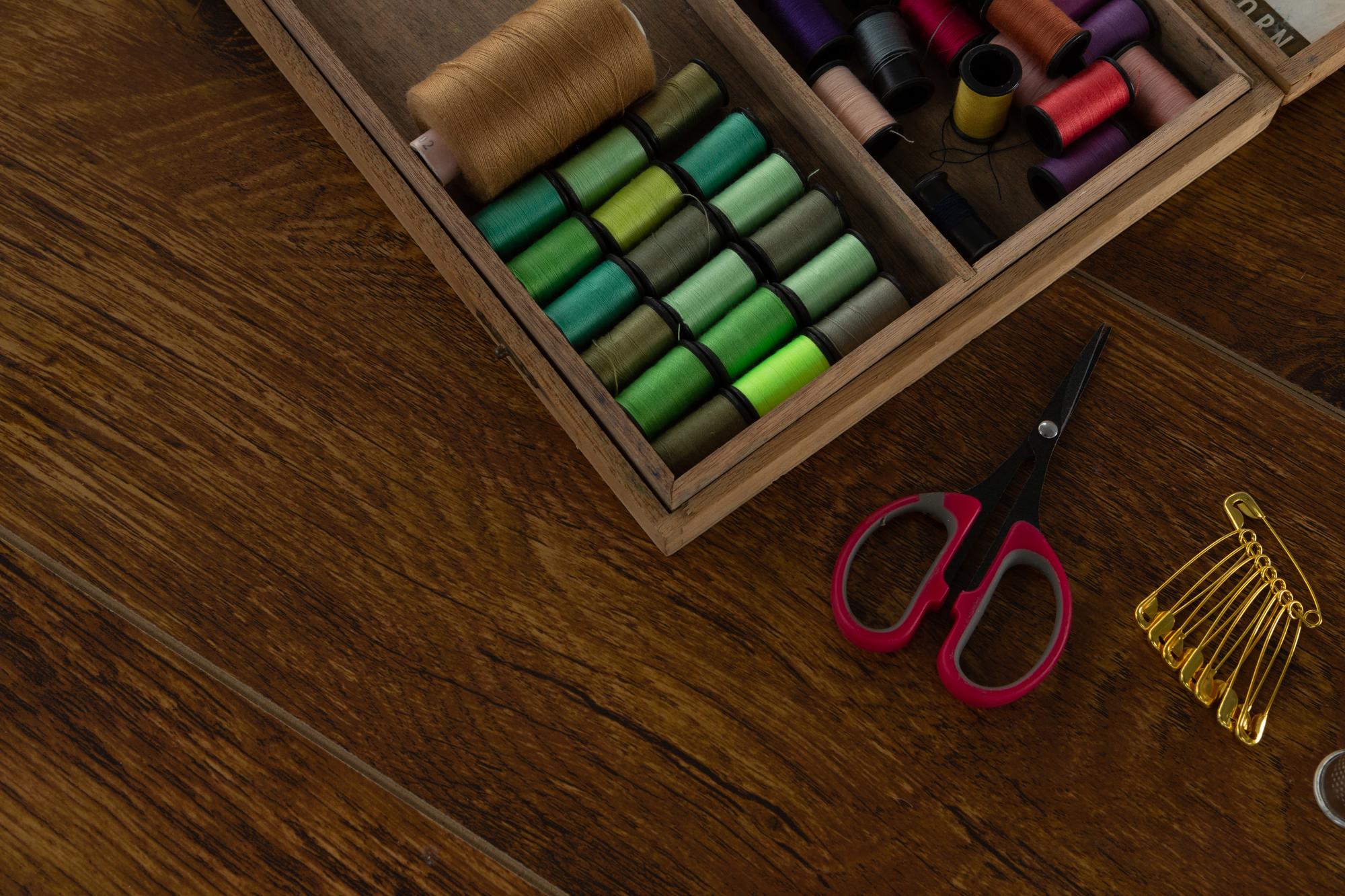 Compact toolkit: threads, needles and hoop on wooden table